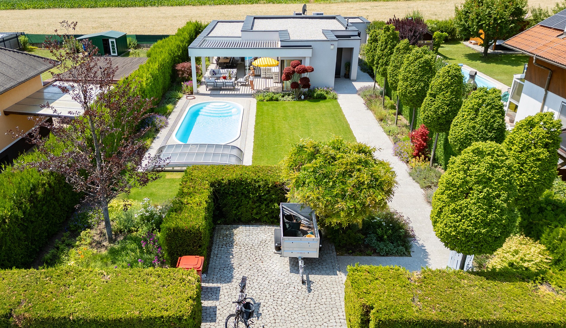 Luftaufnahme eines Gartens mit Pool, Rasenfläche, Allee aus Säulenbuchen und klarer Gartenstruktur.