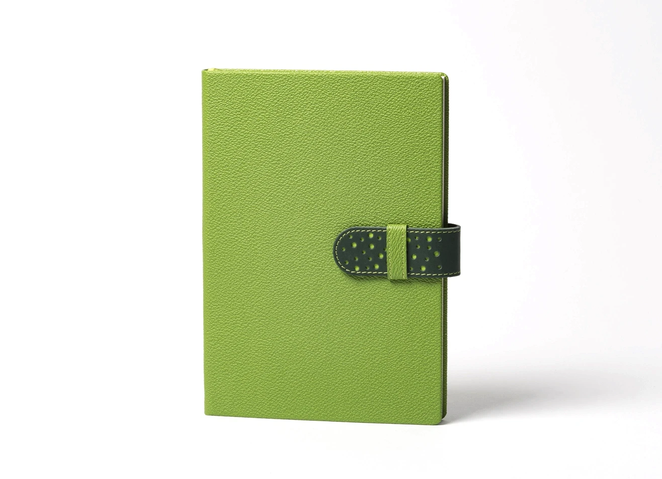 Lime green notebook lying flat with the dark green closure strap unfastened and extended to the right, displaying the loop mechanism.