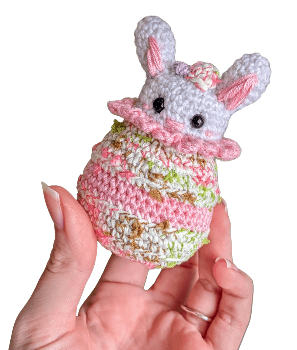 A cute, handcrafted plush acorn toy with brown yarn spikes and large, friendly eyes sits facing forward on a white background.