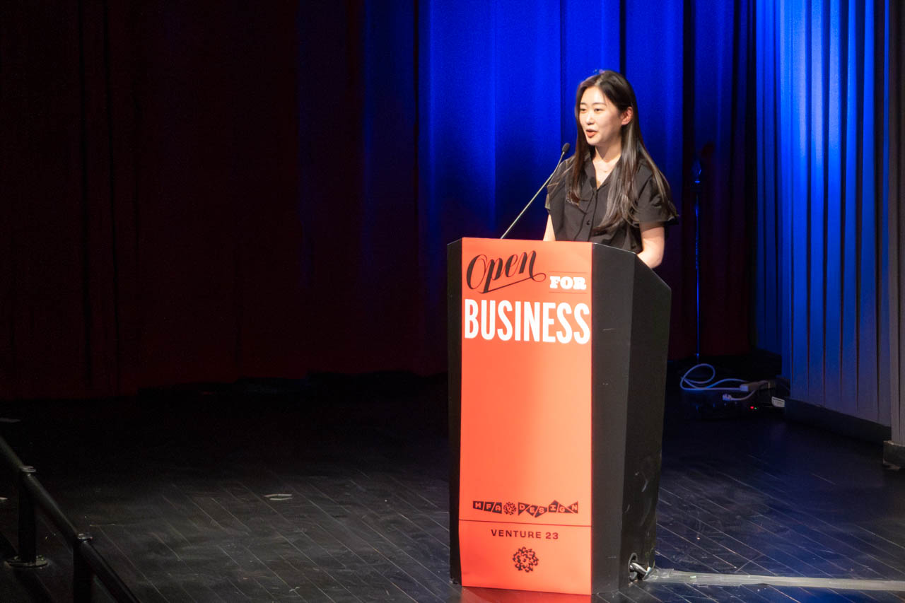 woman standing at a podium delivering a presentation