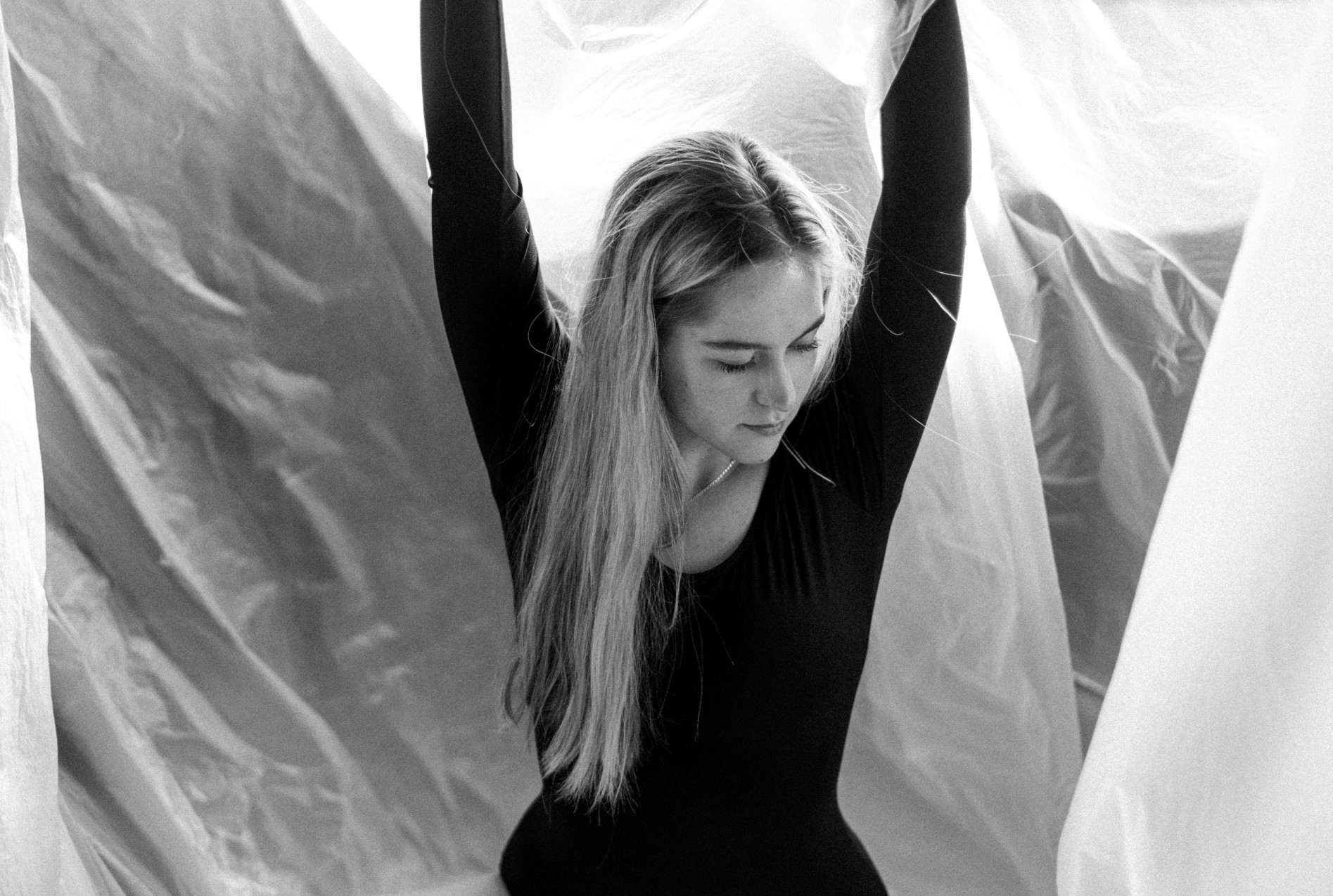 A ballerina with long hair throws her arms up