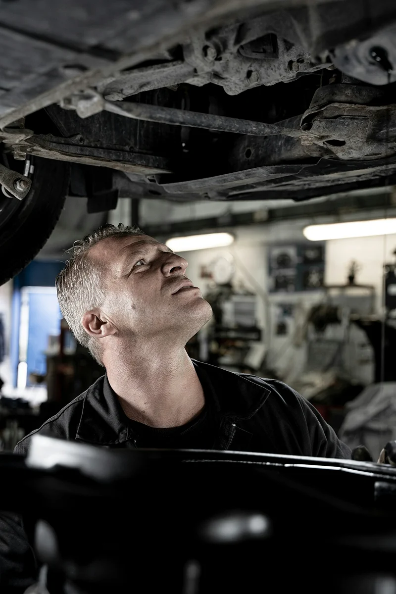 Technician inspecting the underside of a raised vehicle