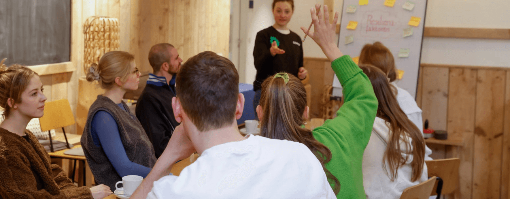 Gruppe von Menschen in einem Workshop, eine Frau meldet sich