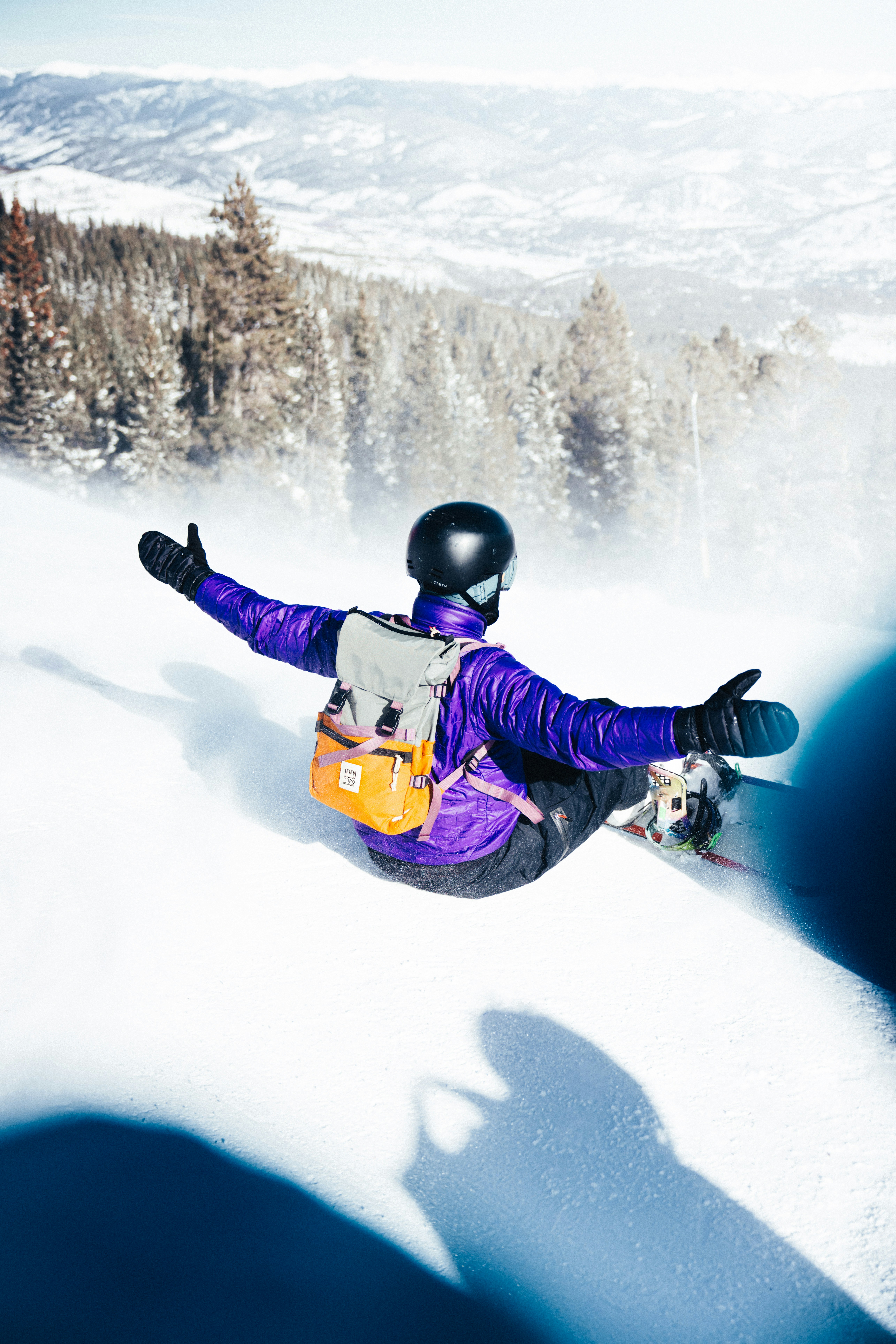 Snowboarder enjoys a downhill run on a sunny day.