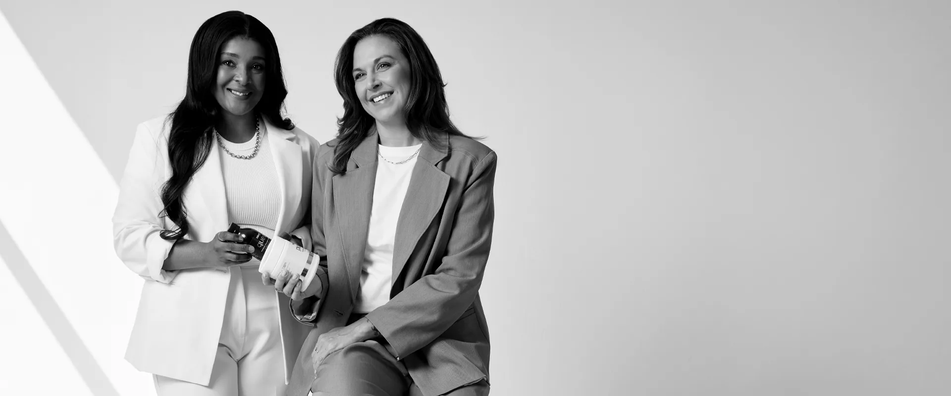 Sēkret founders Roz and Zola with a tub of Pure and a bottle of Queen, in black and white