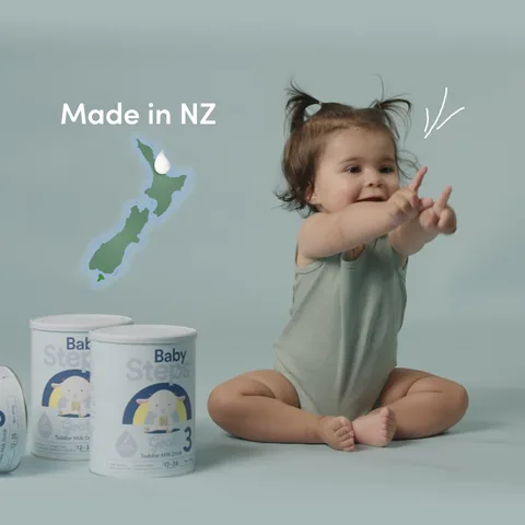 A drawn map of New Zealand beside a toddler and two tins