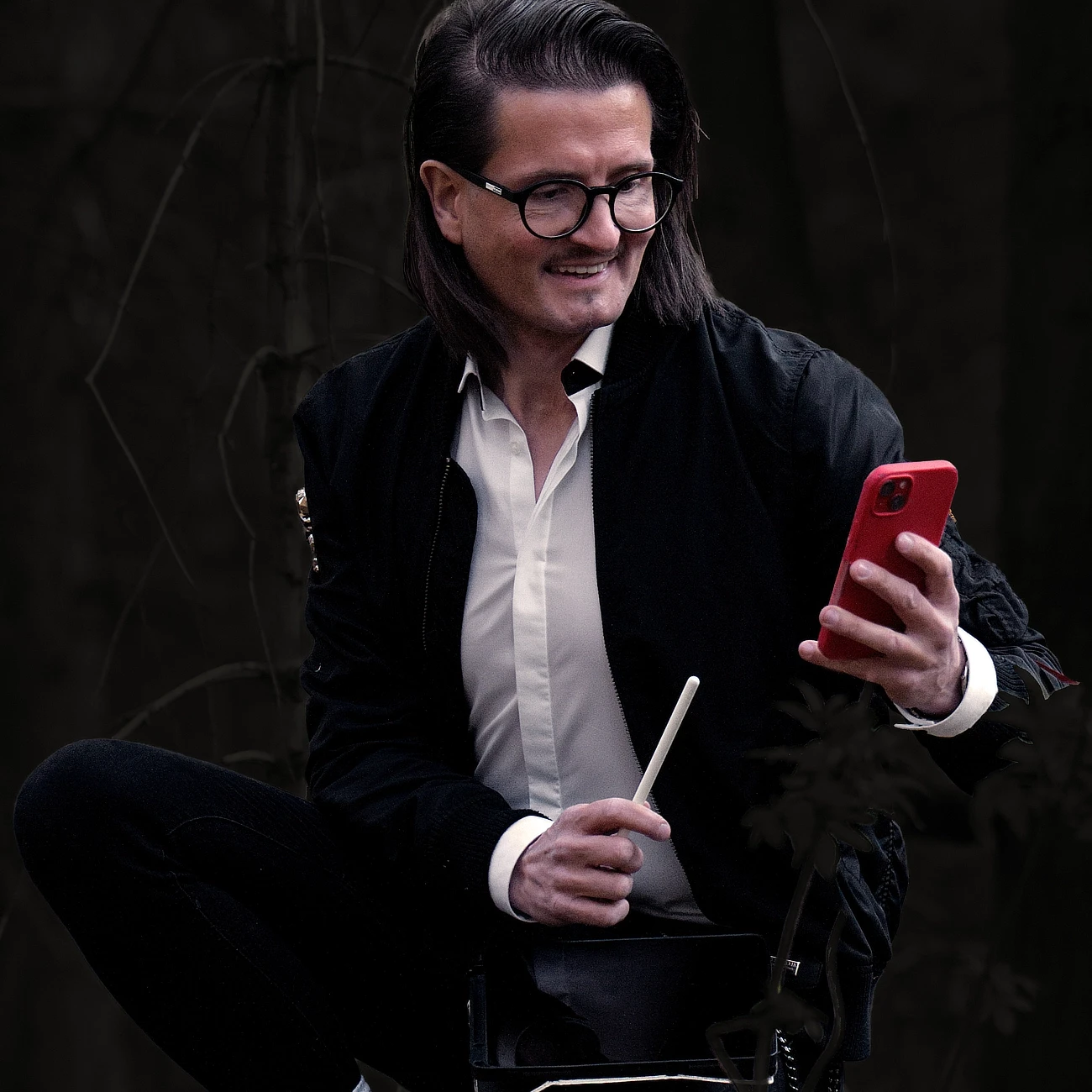 Porträt von Jens Pfeifer, UX/UI-Designer und Gründer von PFiFR Design Intelligence, mit Smartphone in der Hand in dunkler cineastischer Atmosphäre.