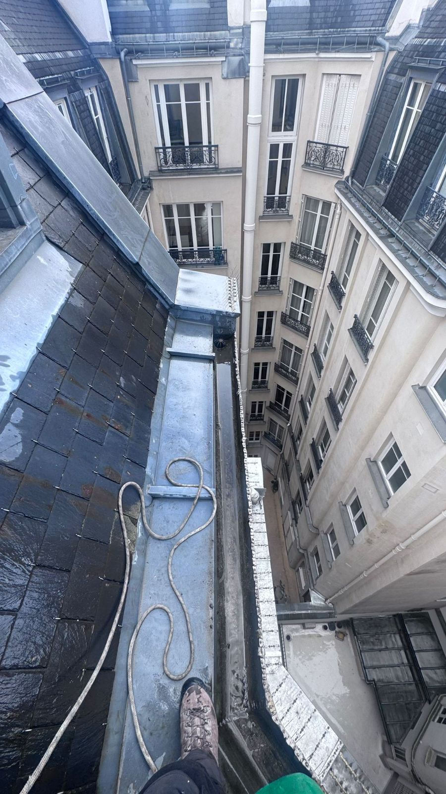 Accès cordiste à un chéneau côté cour, Paris 16e Chéneau encaissé côté cour vu depuis le bord d'une toiture en ardoise, corde de cordiste posée, cour d'immeuble en contrebas