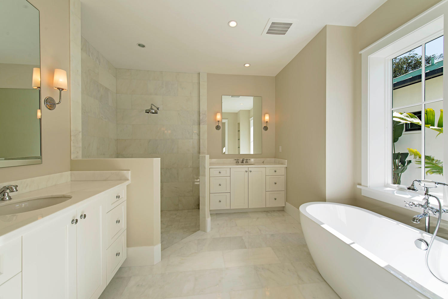a luxurious bathroom with white tiles and natural light shining from a window on the right wall over the tub