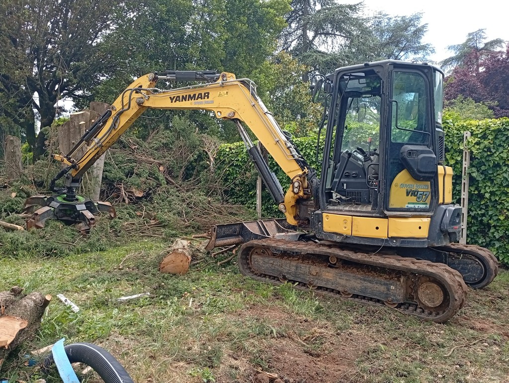 cingolato con ragno solleva tronchi e sfalci da terra liberando una zona di giardino privato
