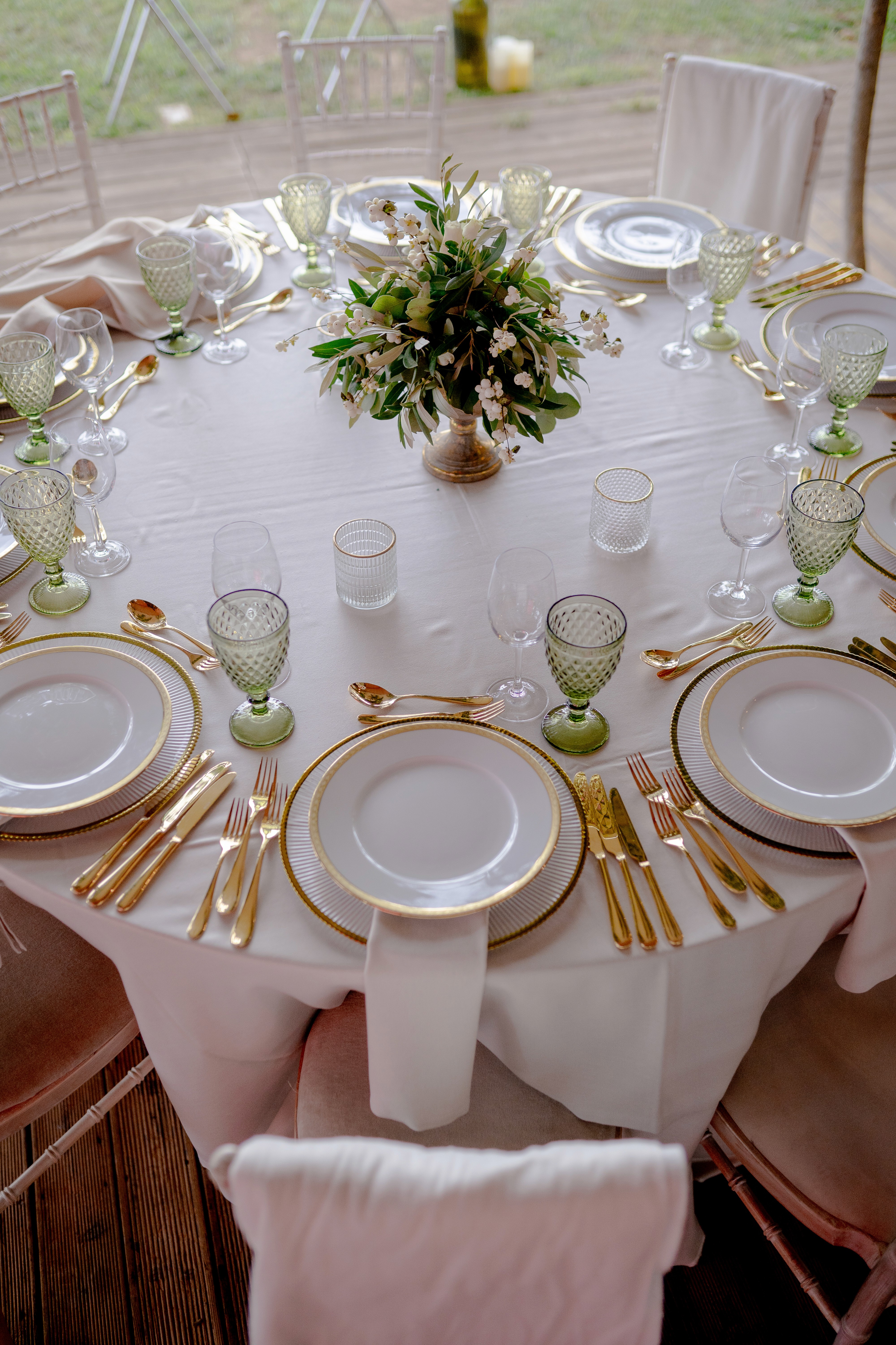 A couple stands hand-in-hand in front of a rustic stone building.