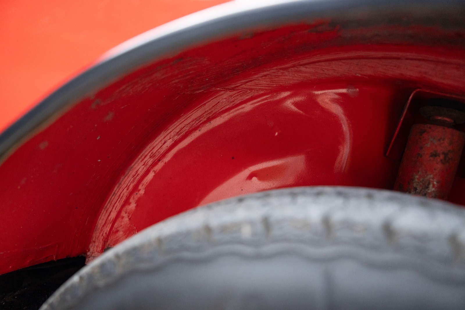 Close-up of a tire and wheel arch, featuring a vibrant red background and sleek grey tire.