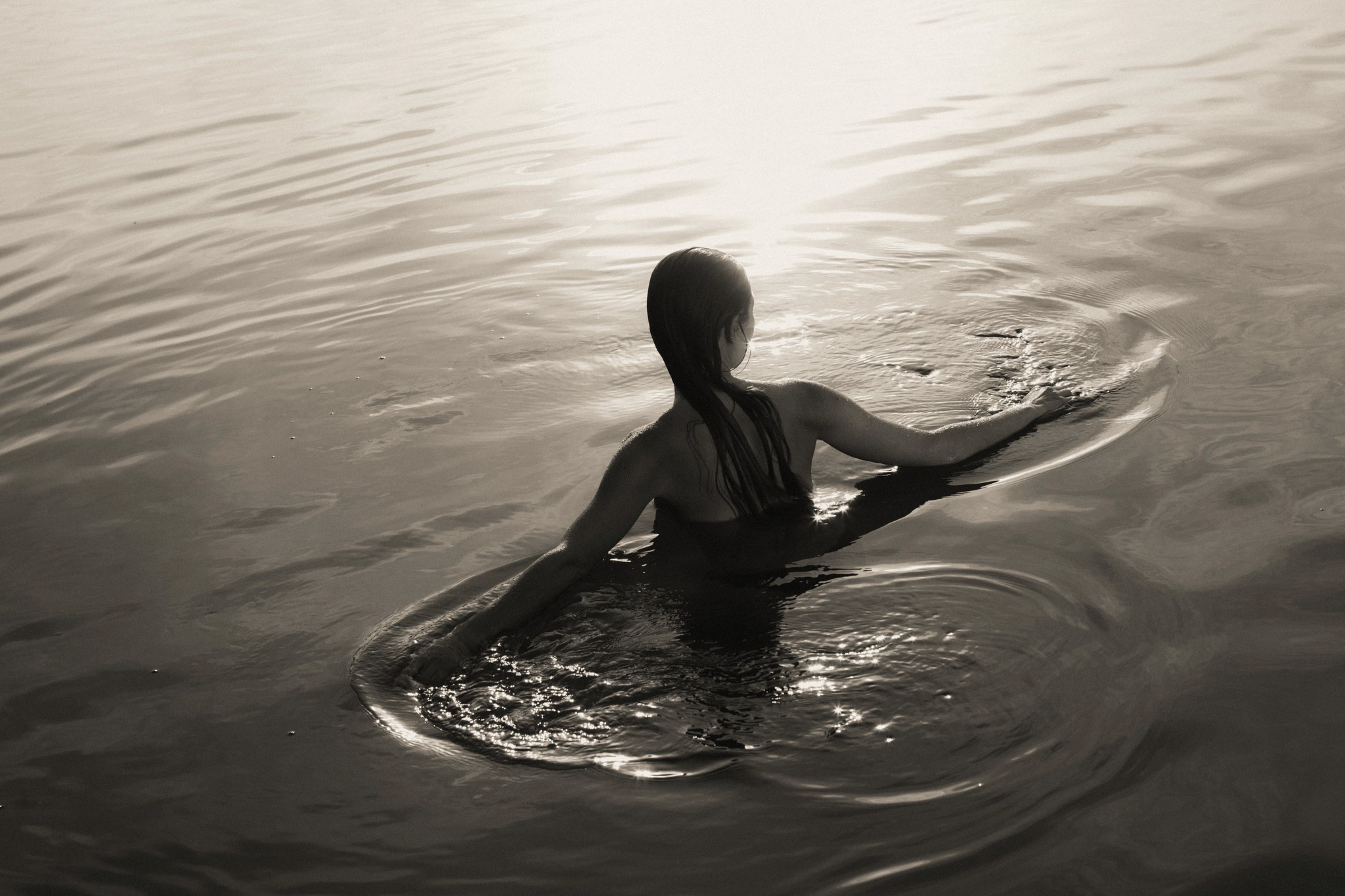 Frau schwimmt ruhig im Wasser im Gegenlicht der Sonne