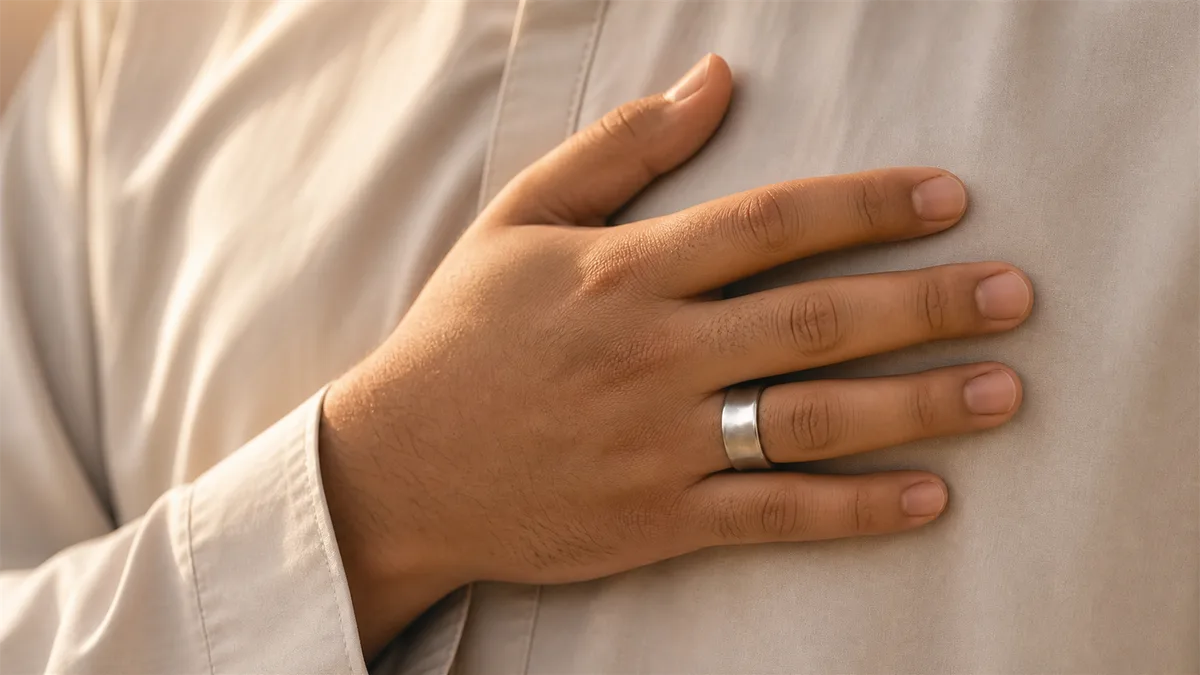 Hand over heart wearing a silver smart tasbih ring in warm light for khushu during dhikr