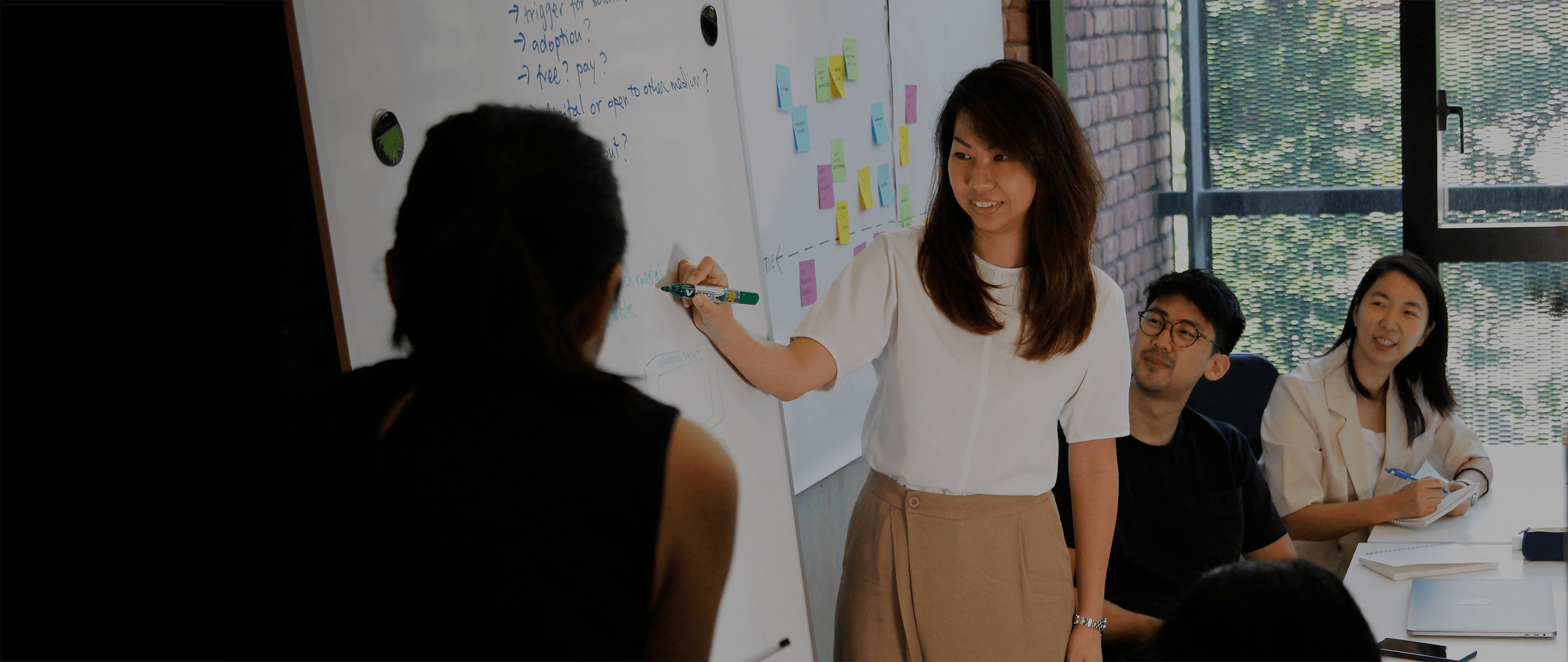 An image of Wendy, our Co-Founder and Head of 55 Minutes, leading a discussion at a whiteboard while other members listen and take notes.