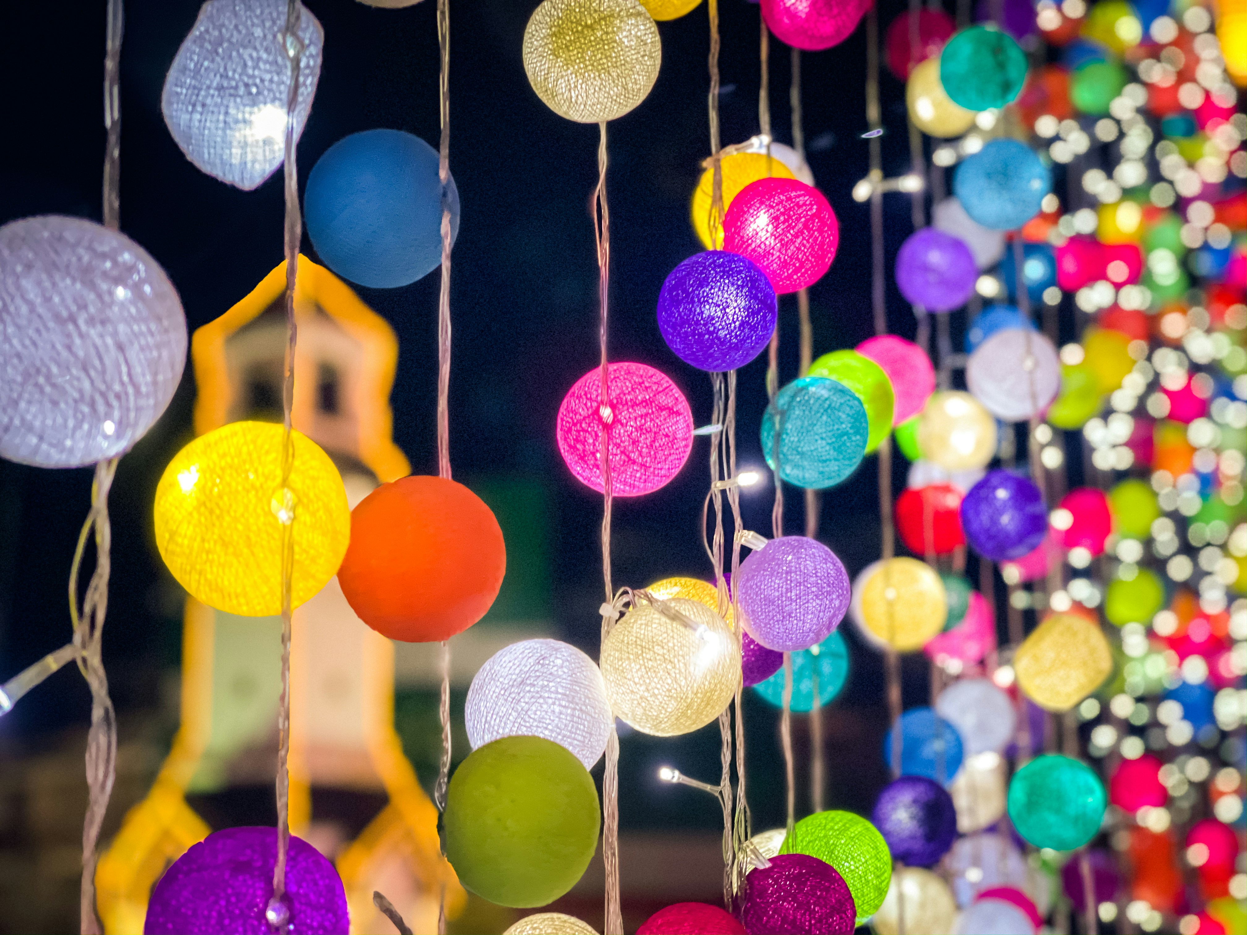 a bunch of colorful balls hanging from strings