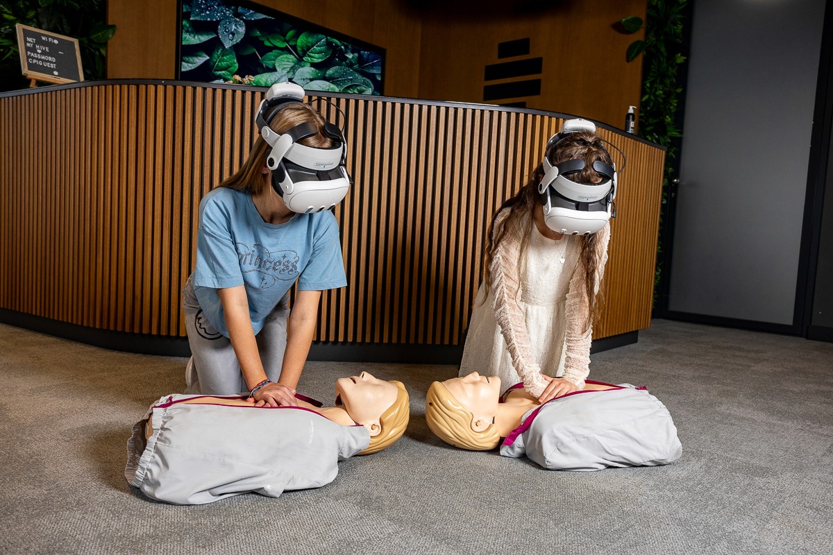Children performing CPR or first aid using mannequins and VR technology.