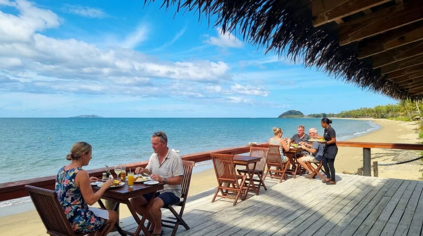 2 couples enjoying lunch at the beach front bar at Uprising Resort, Fiji served by a female staff member