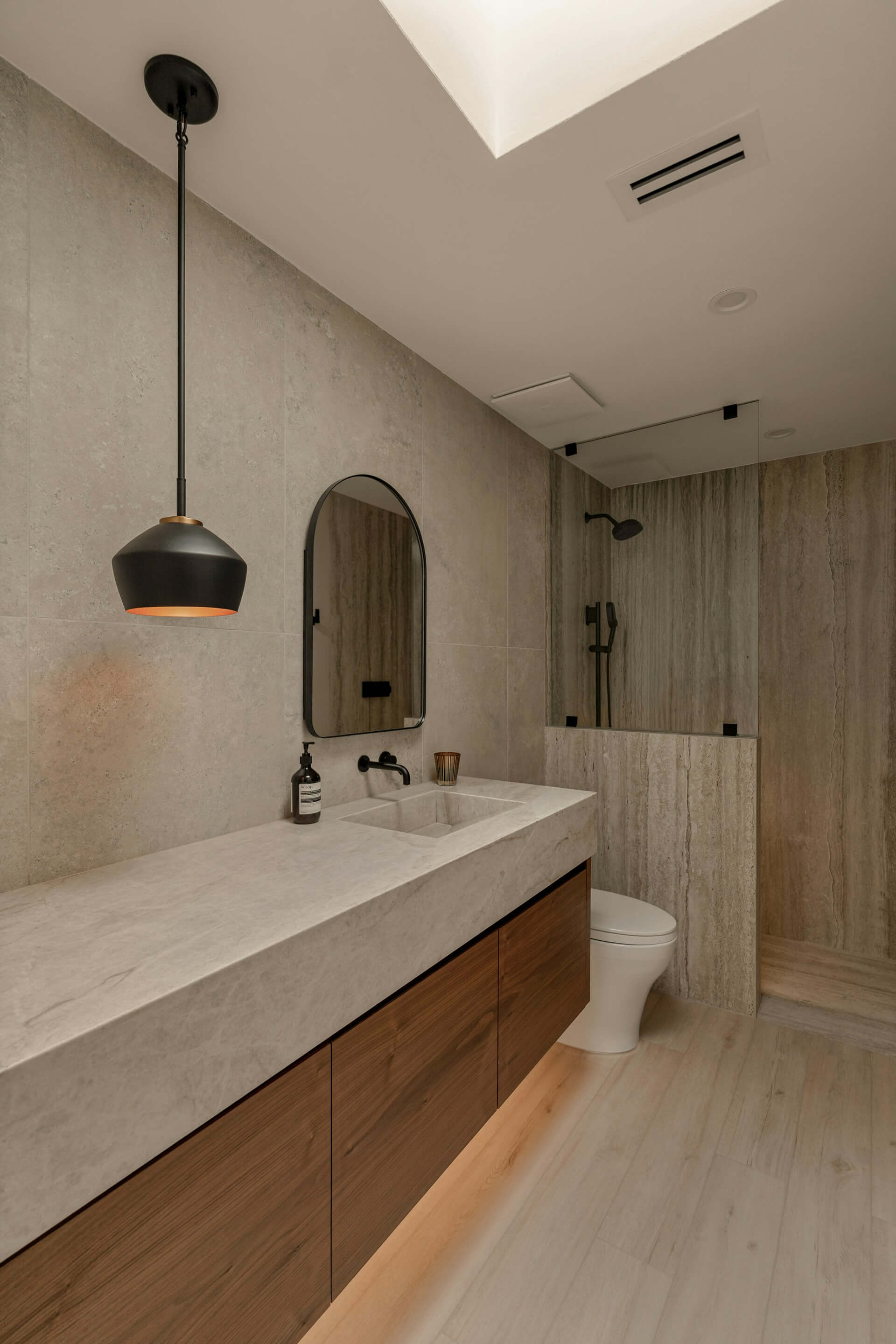 Modern bathroom lighting design featuring pendant lights and warm LED glow against stone textures.