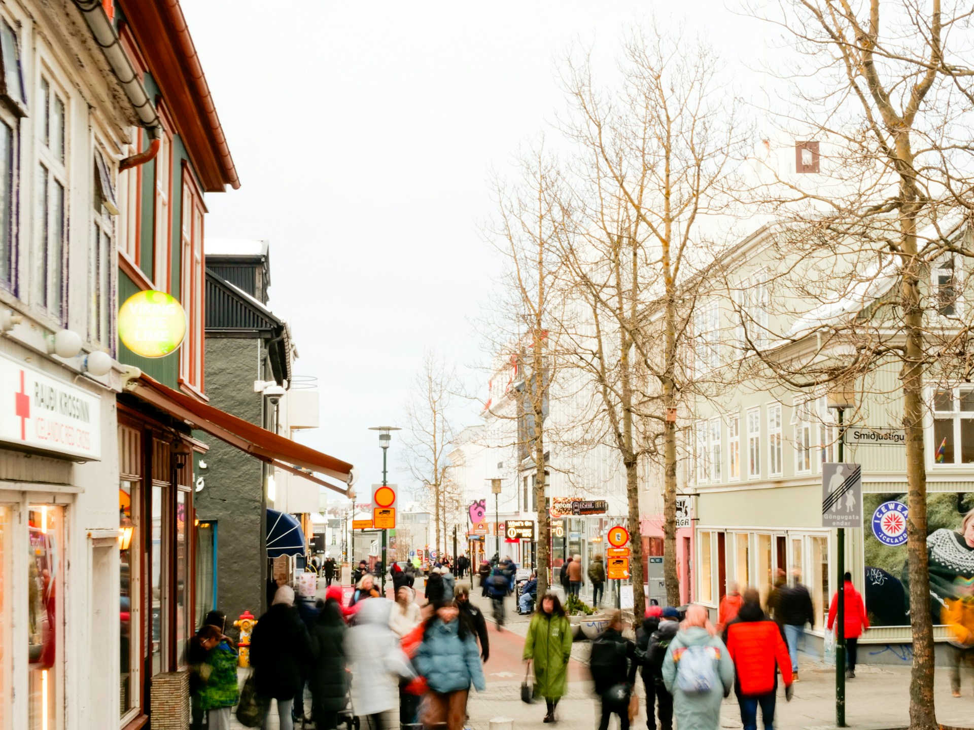 Pedestrians walking along Laugavegur, Reykjavík's main shopping street, lined with colorful shops, cafés, and local businesses.
