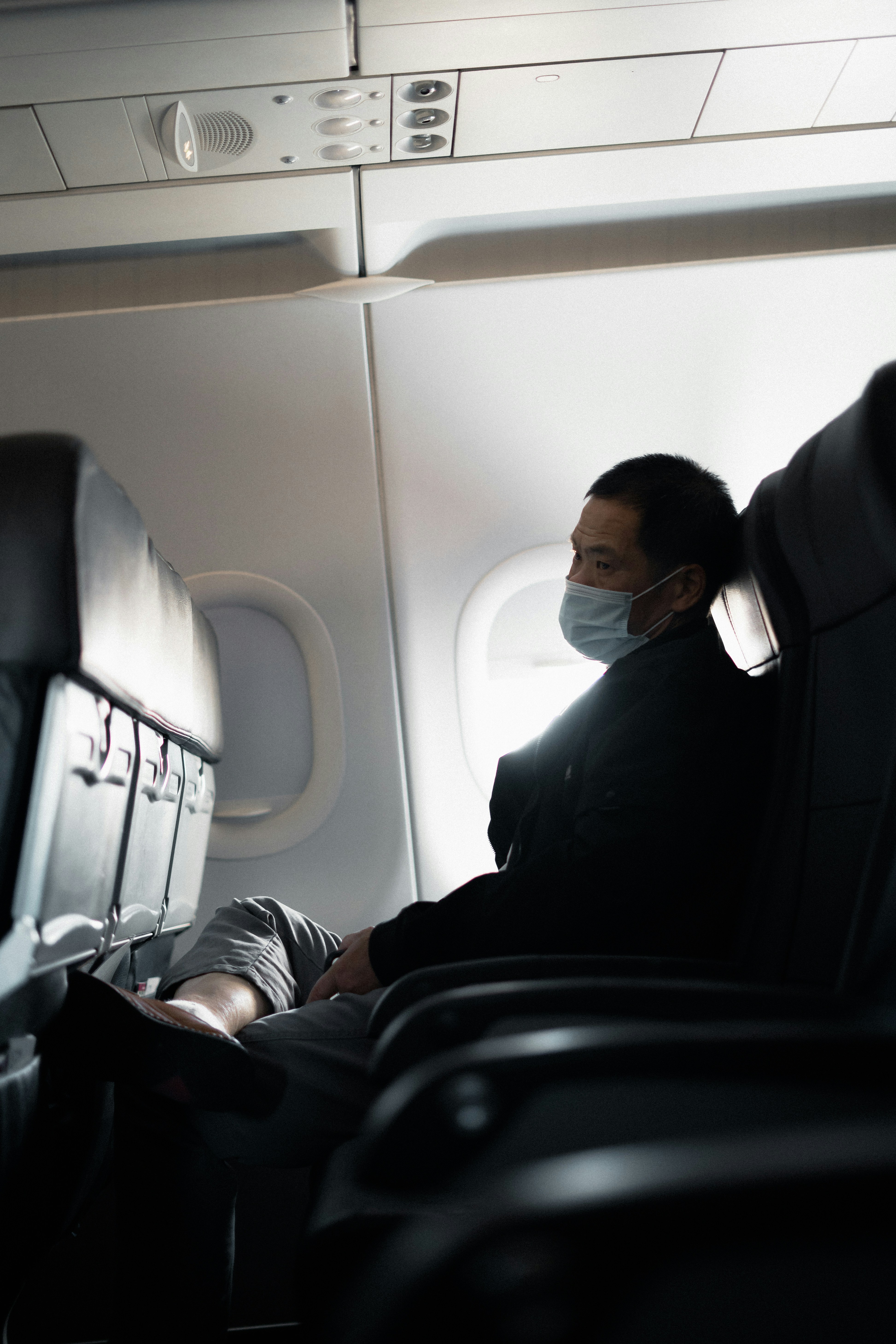 man in black suit sitting on airplane seat