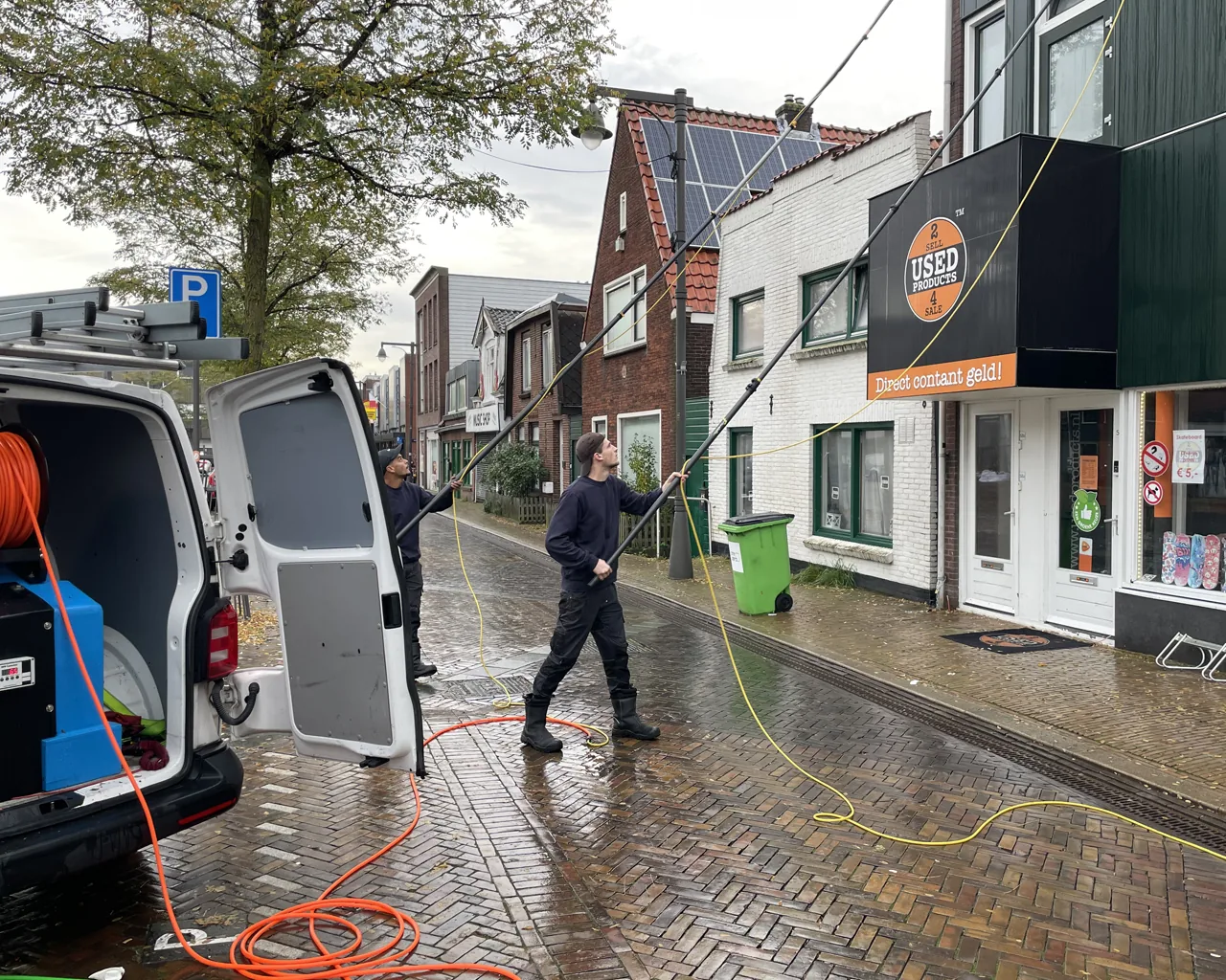 Het team van Qlean Facility Group aan het werk met telescoopstelen in een winkelstraat