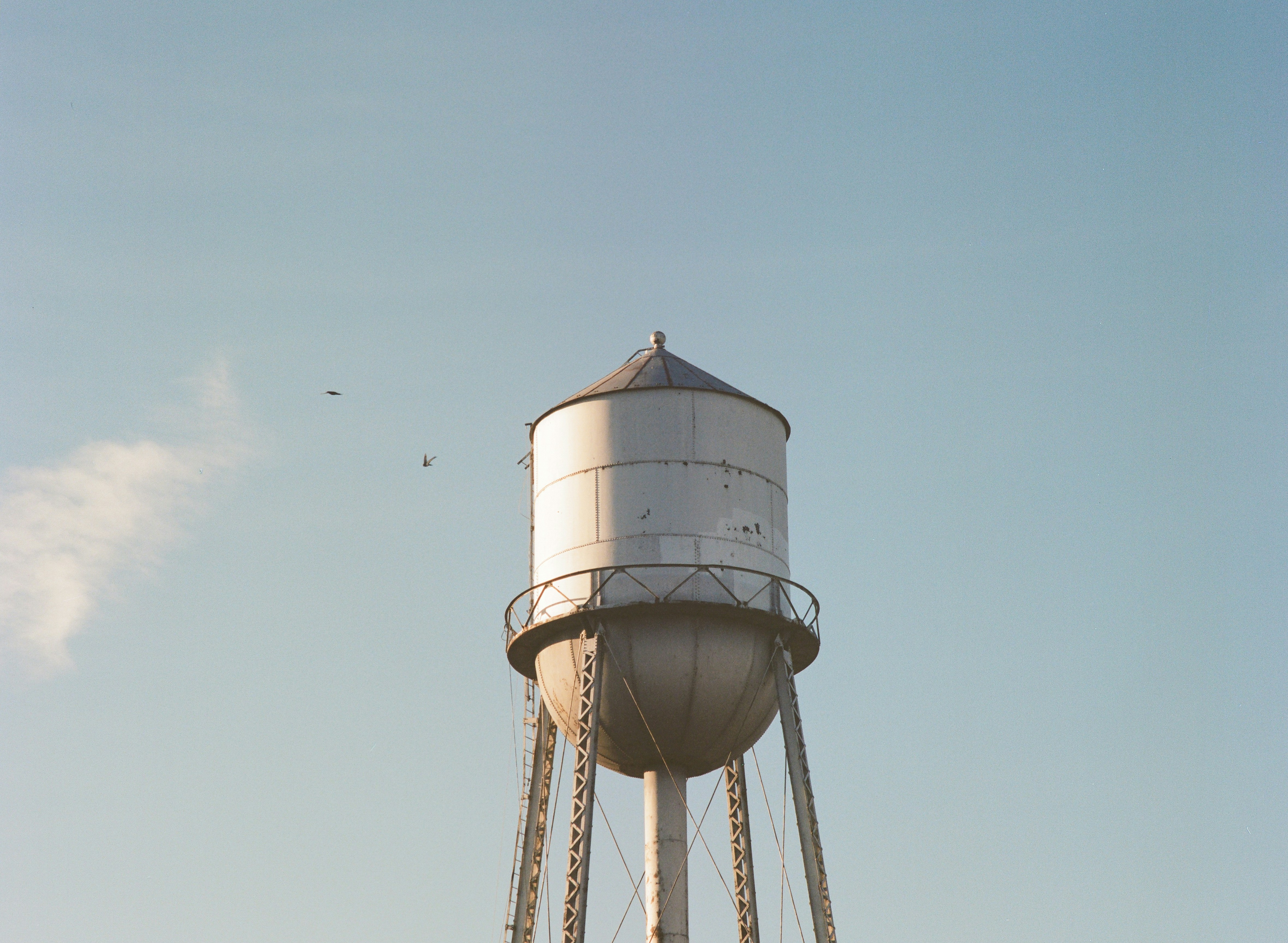 a large white water tower with a sky background