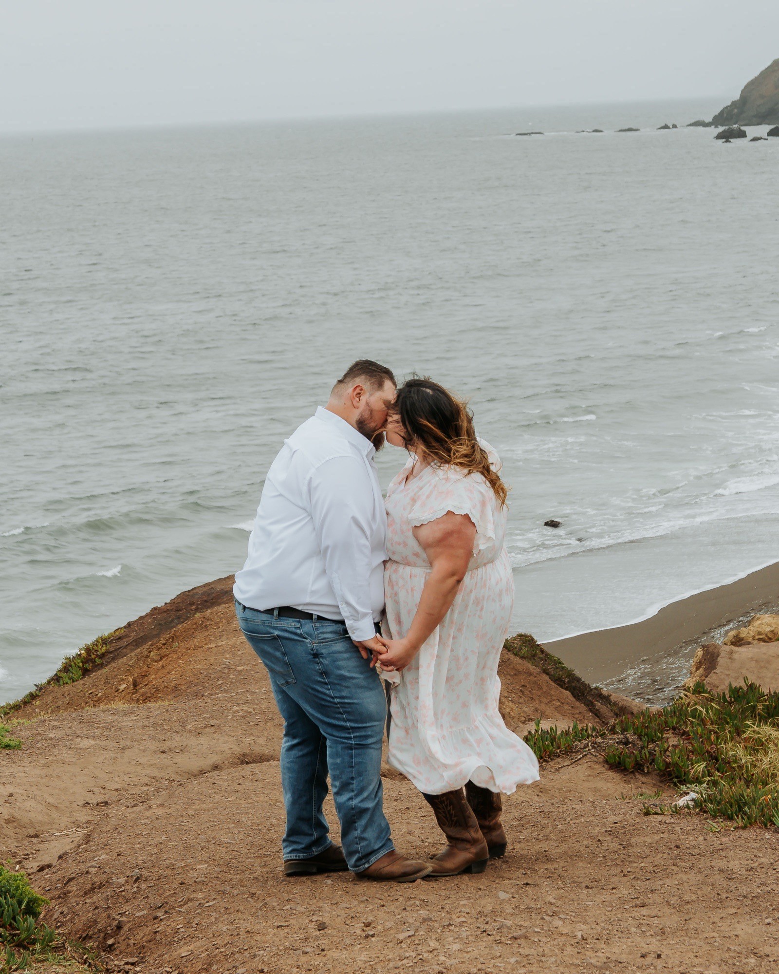 Pareja besándose en un acantilado frente al mar