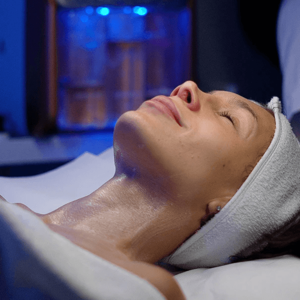 Cosmetologist marking a woman's face with a pencil during a cosmetic procedure, wearing blue gloves