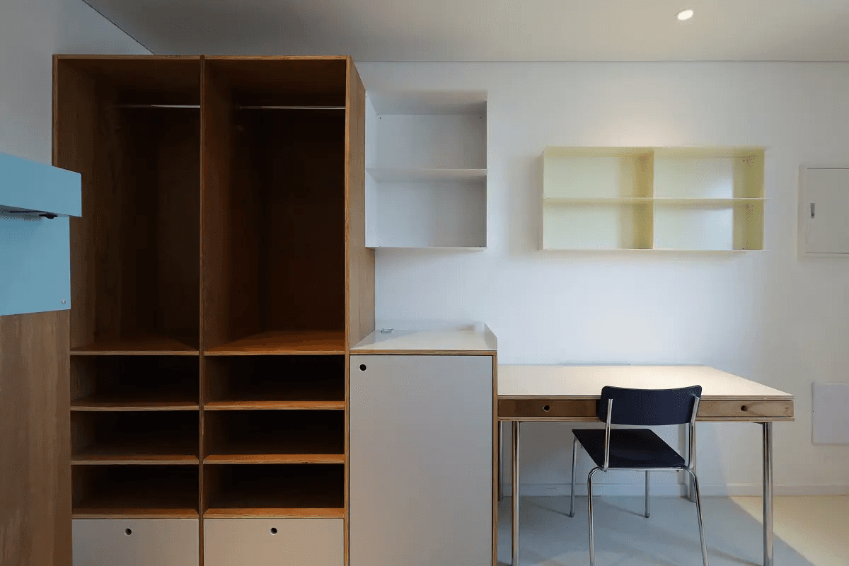 A woman with her hair tied back smiles while reading an open book in the library at Mangrove Sinchon.