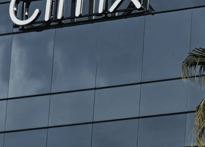 Close-up of a modern glass office building exterior with partial company signage visible at the top.