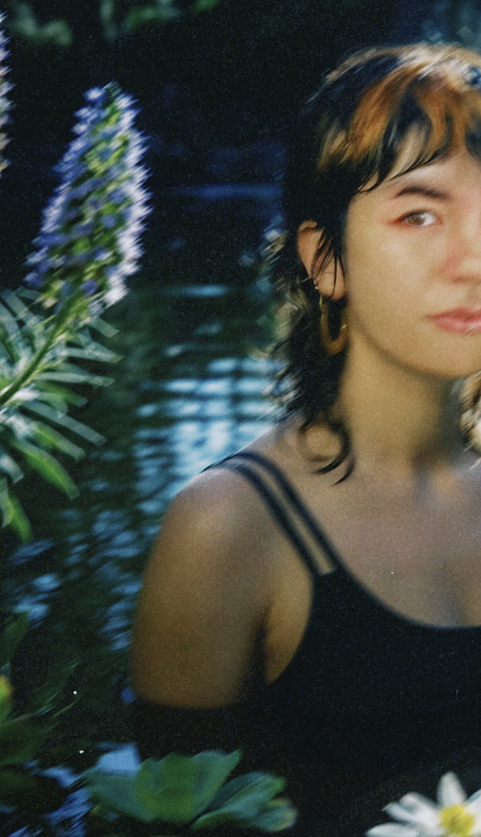 A person attentively paints a vibrant, expressive artwork of two people embracing, featuring bold colors like pink, blue, and green, highlighting themes of love and closeness in the painting.