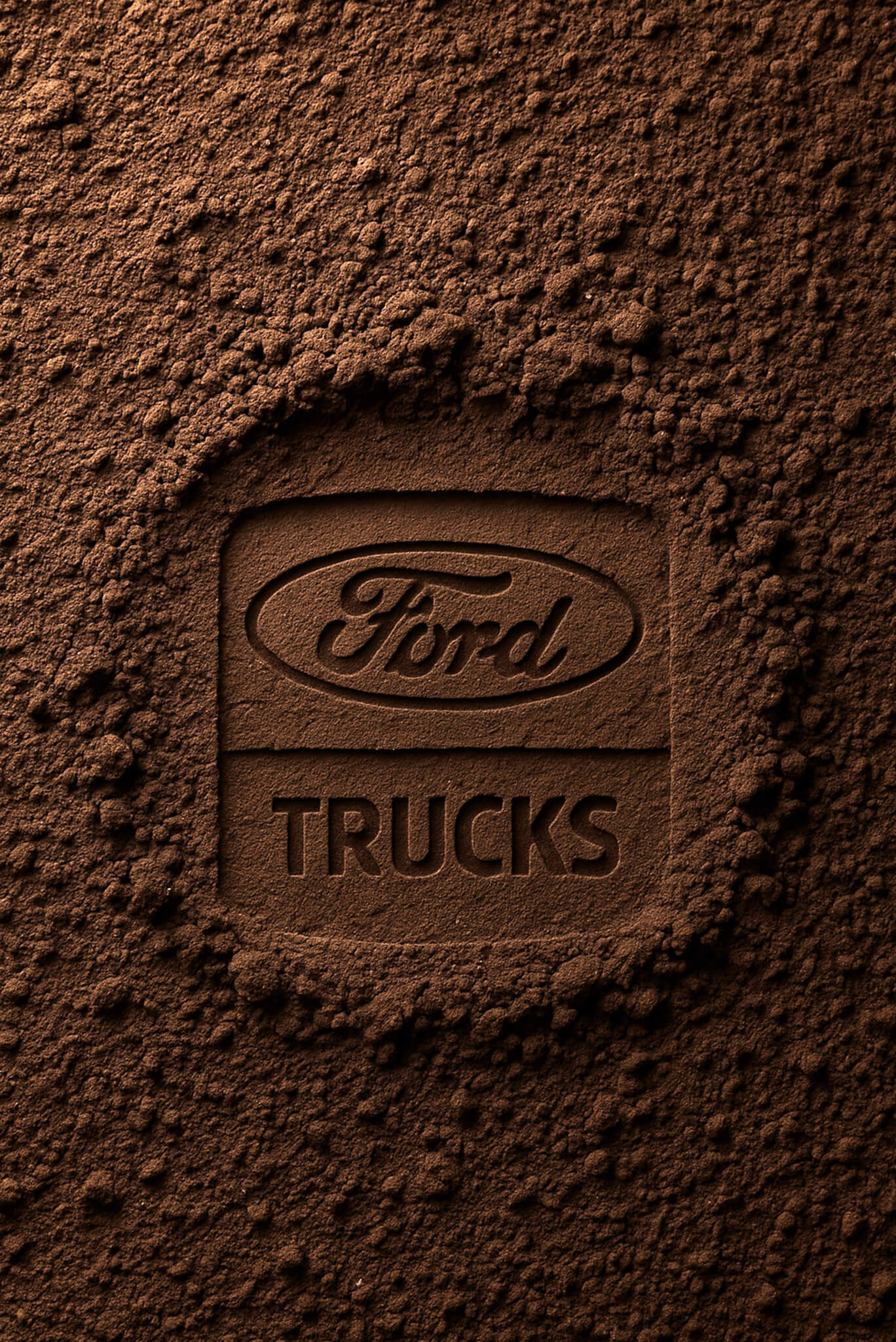Ford Trucks logo embossed in textured soil, symbolizing rugged durability and heavy-duty performance.