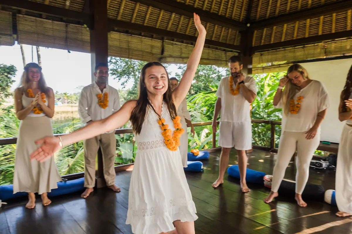 Group of happy graduates holding their yoga teacher training certificates overlooking the ocean after completion.