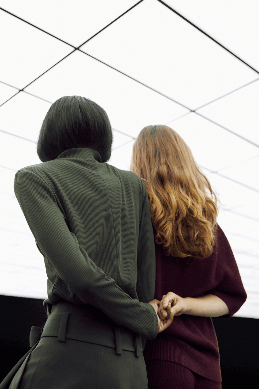 A man in a grey shirt sits in a dim office, gazing seriously at a computer screen. Blinds and office supplies create a focused and professional atmosphere.