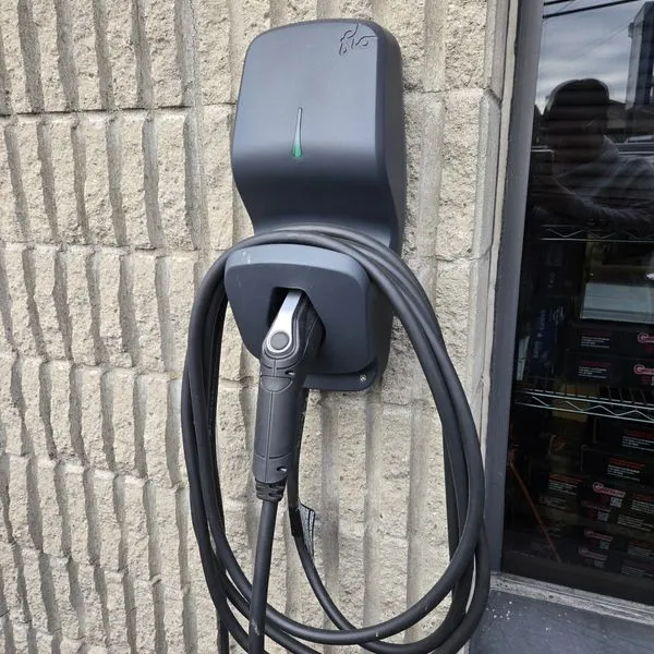 Borne de recharge pour véhicule électrique installée sur le mur extérieur du Garage Claude Coutu  Souhaites-tu que je t’aide à organiser toutes ces images dans une maquette de footer cohérente ?