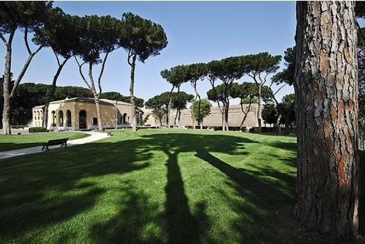 A photo of a green park with trees near some ancient stone buildings in Rome.