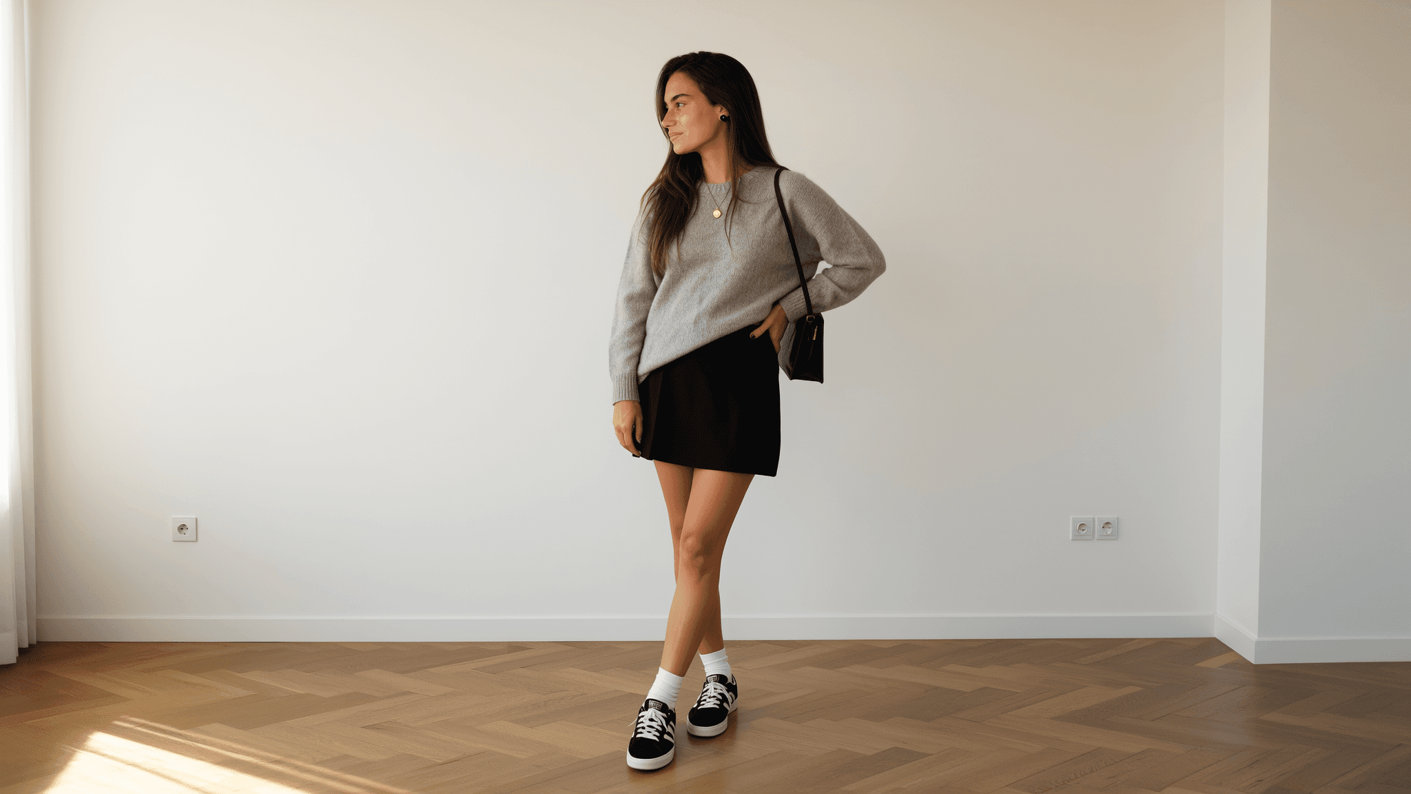 KI-generiertes weibliches Model in minimalistischem Outfit trägt grauen Strickpullover, schwarzen Minirock und schwarz-weiße Sneakers; moderner Clean-Girl-Look für Fashion- und Lifestyle-Content.