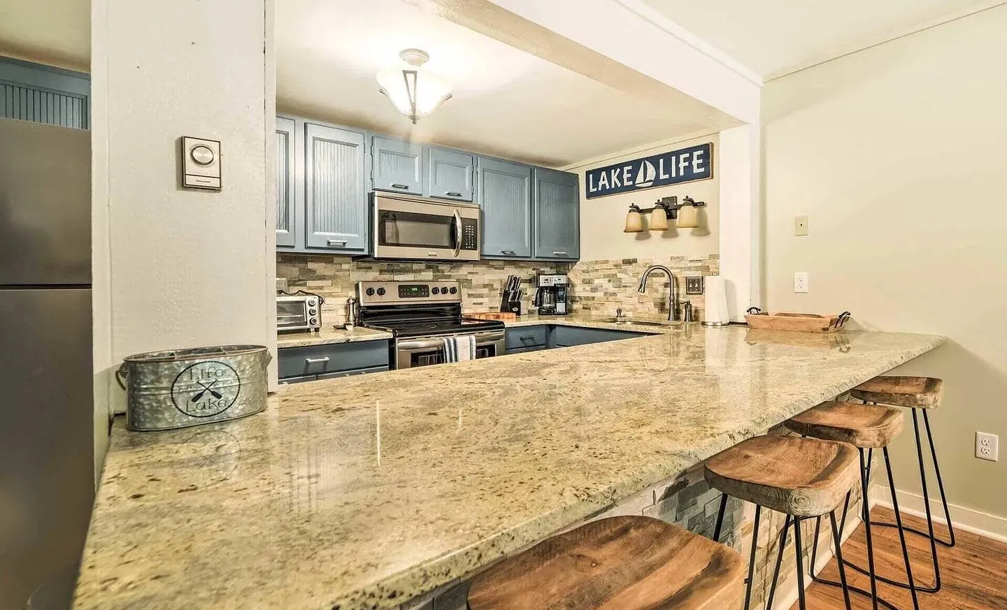 Granite breakfast bar with wood stools and blue cabinets at Big Boulder Lake & Ski House