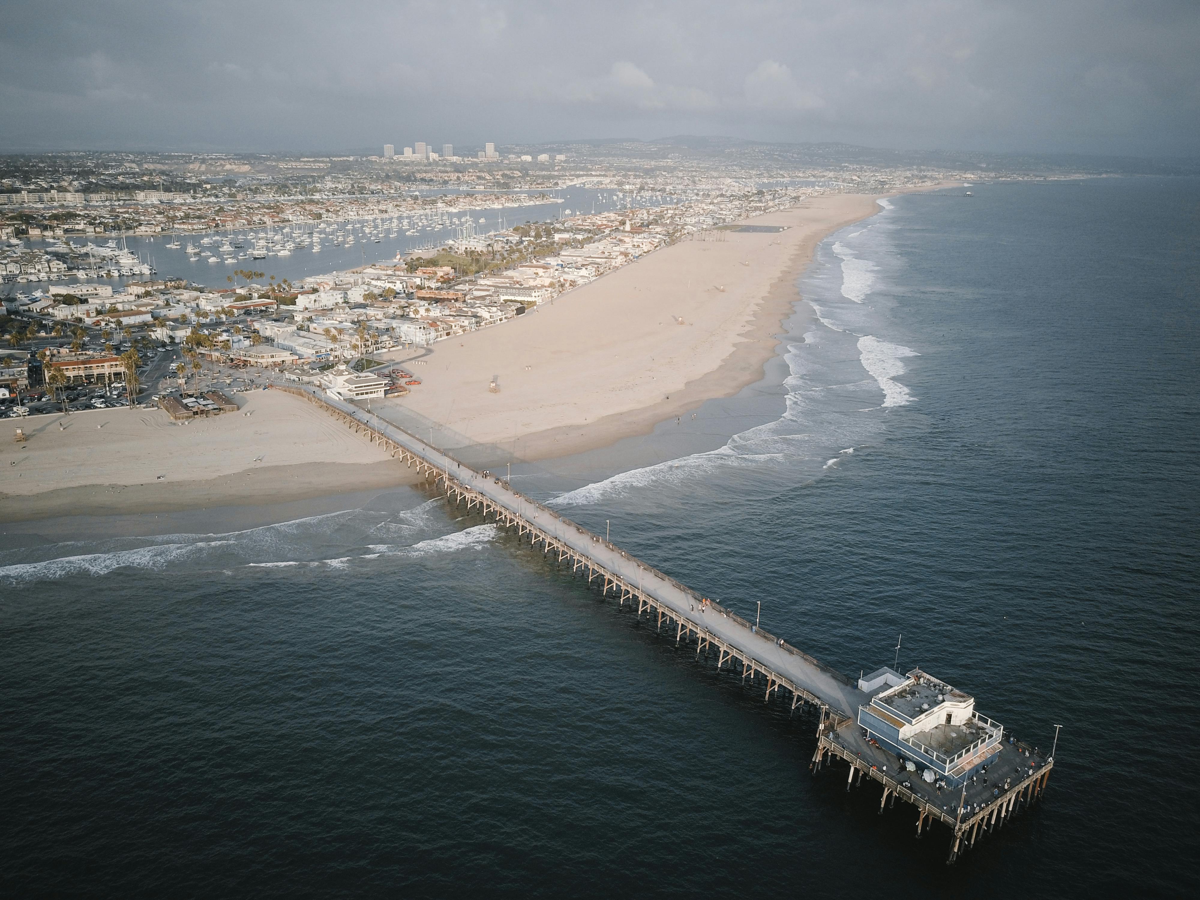 Aerial view of a long pier extending into ocean – surfboard rental in newport-beach