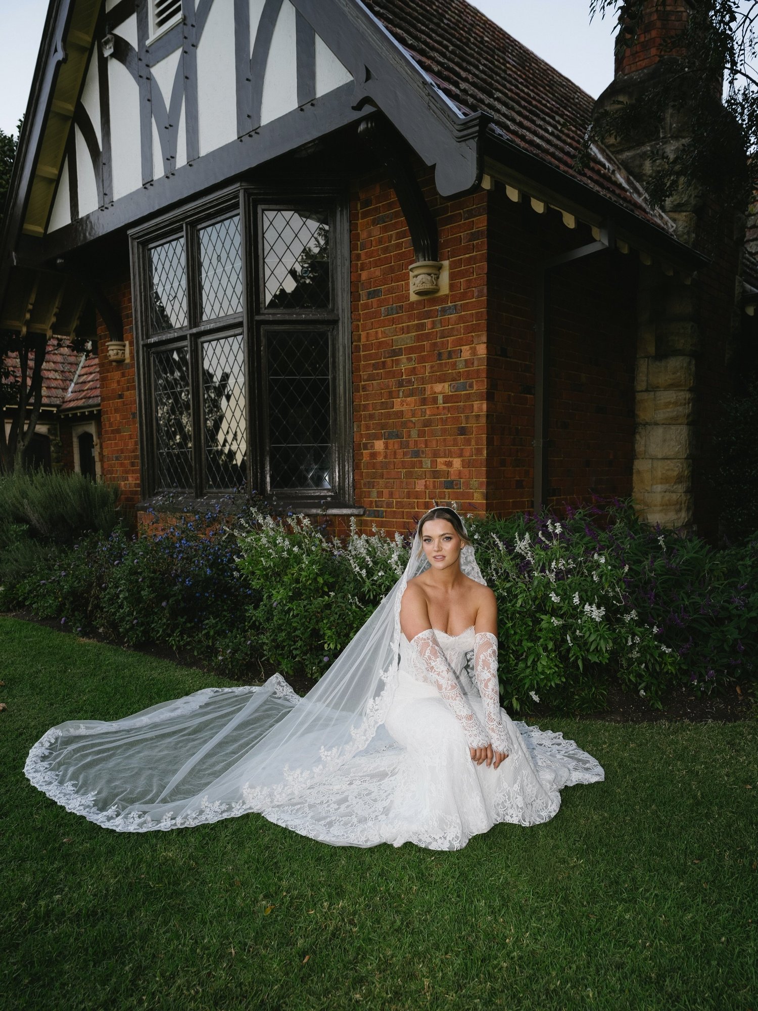 Bride seated on the lawn for an editorial wedding portrait outside a heritage venue