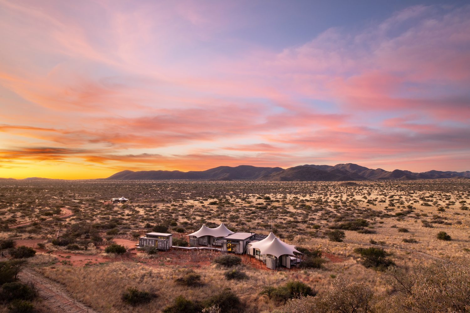 Aerial view of a tented Kalahari camp beneath a pink evening sky