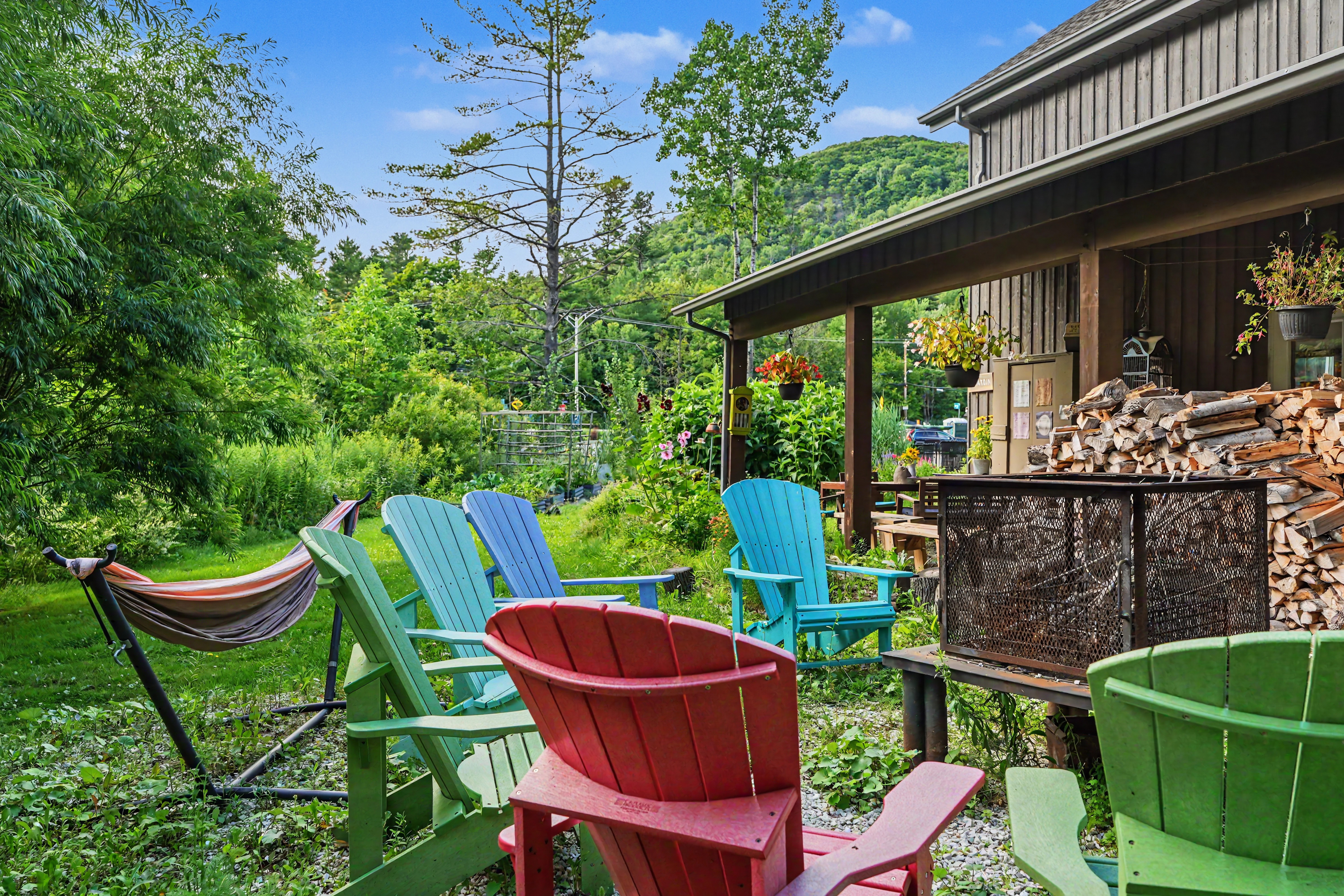 Jardin du gîte R112 Nord à Austin, avec vue sur les montagnes verdoyantes sous un ciel bleu parsemé de nuages, panneau en bois « Le Jardin » au premier plan.