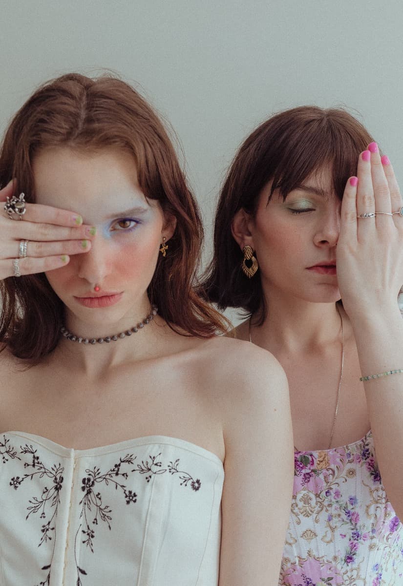 Two models posing with their hands partially covering their faces, highlighting the creative styling of this natural light photoshoot at Revelator Studio, a Shreveport photography studio.