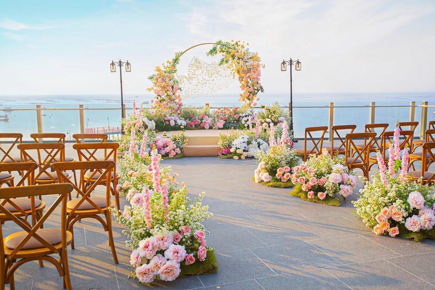 Tiered stone fountain decorated with white roses and greenery for wedding ceremony