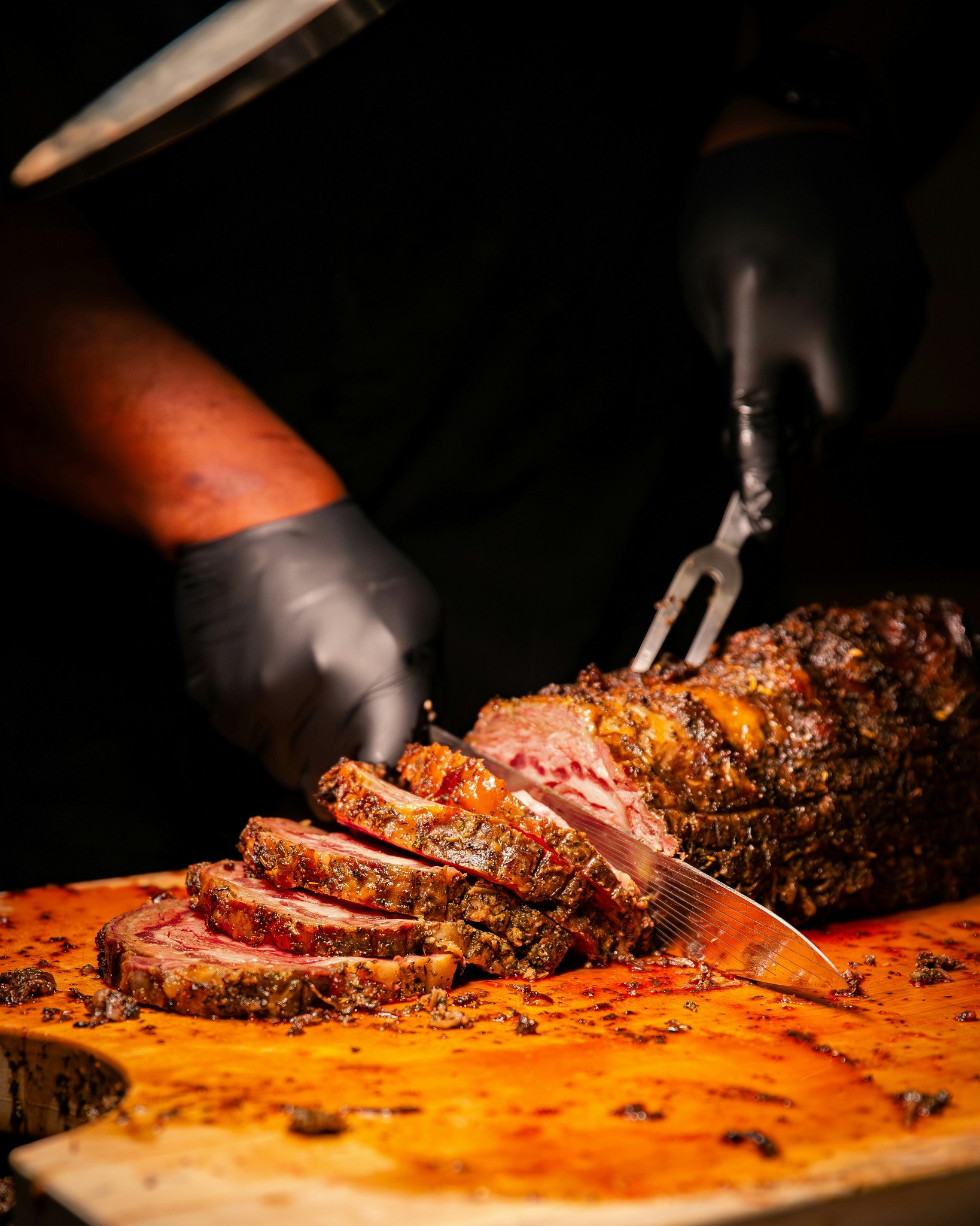 A person cutting a large piece of meat on a cutting board
