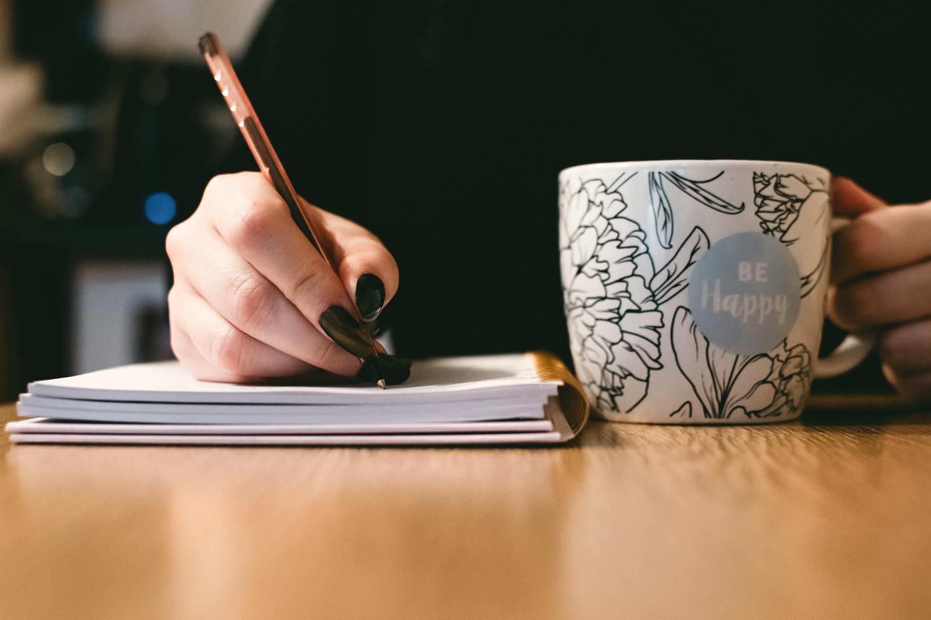 A relaxed educator sitting in a sunny breakroom holding a coffee mug and listening to podcasts for teachers.