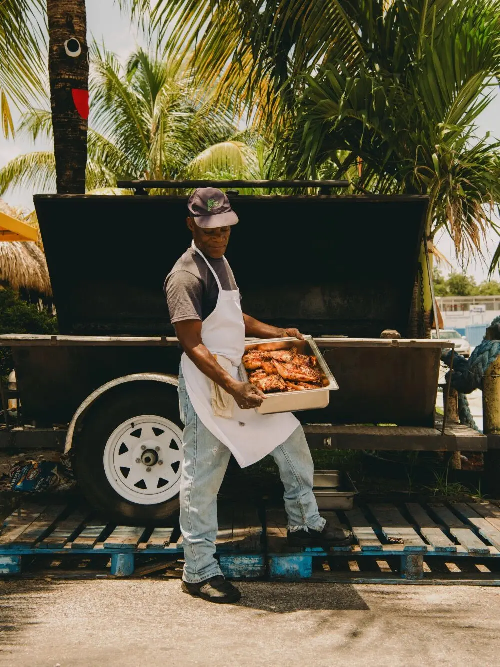 Big Jerk’s responsible cousin carrying a tray of fresh jerk chicken from the smoker