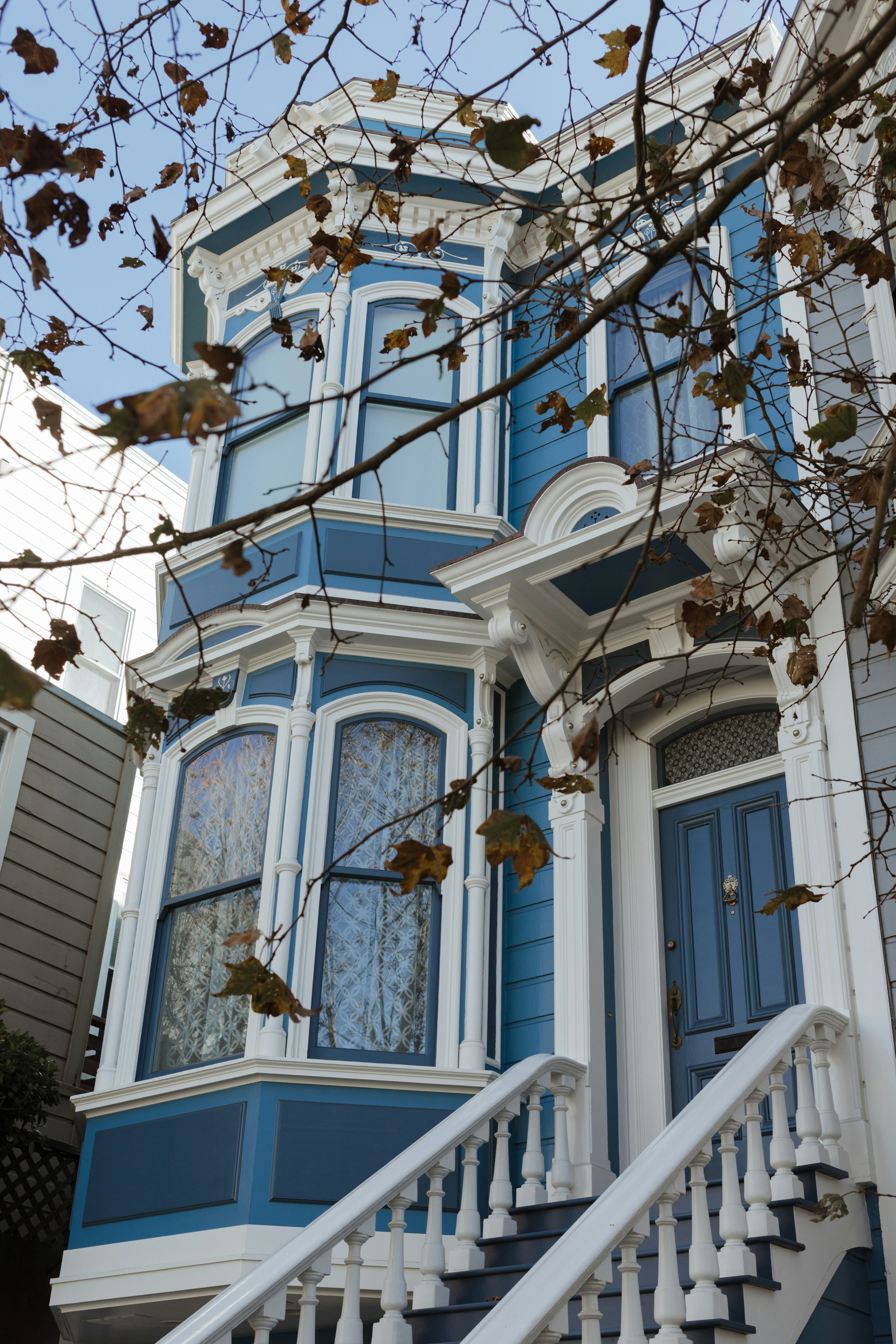 A blue victorian house with white trim and stairs.