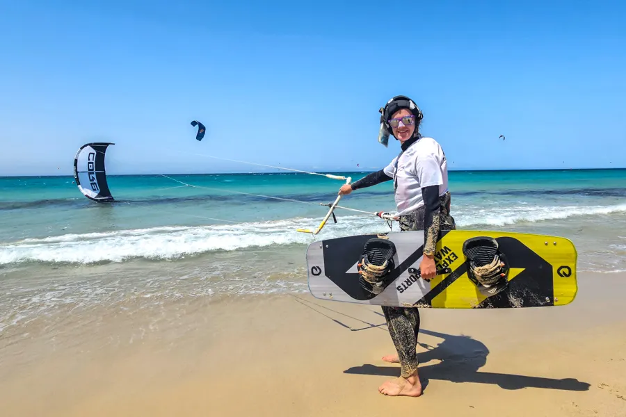 Independent kitesurfer walking up the beach with kiteboard after an advanced kite course — Explora Watersports Tarifa